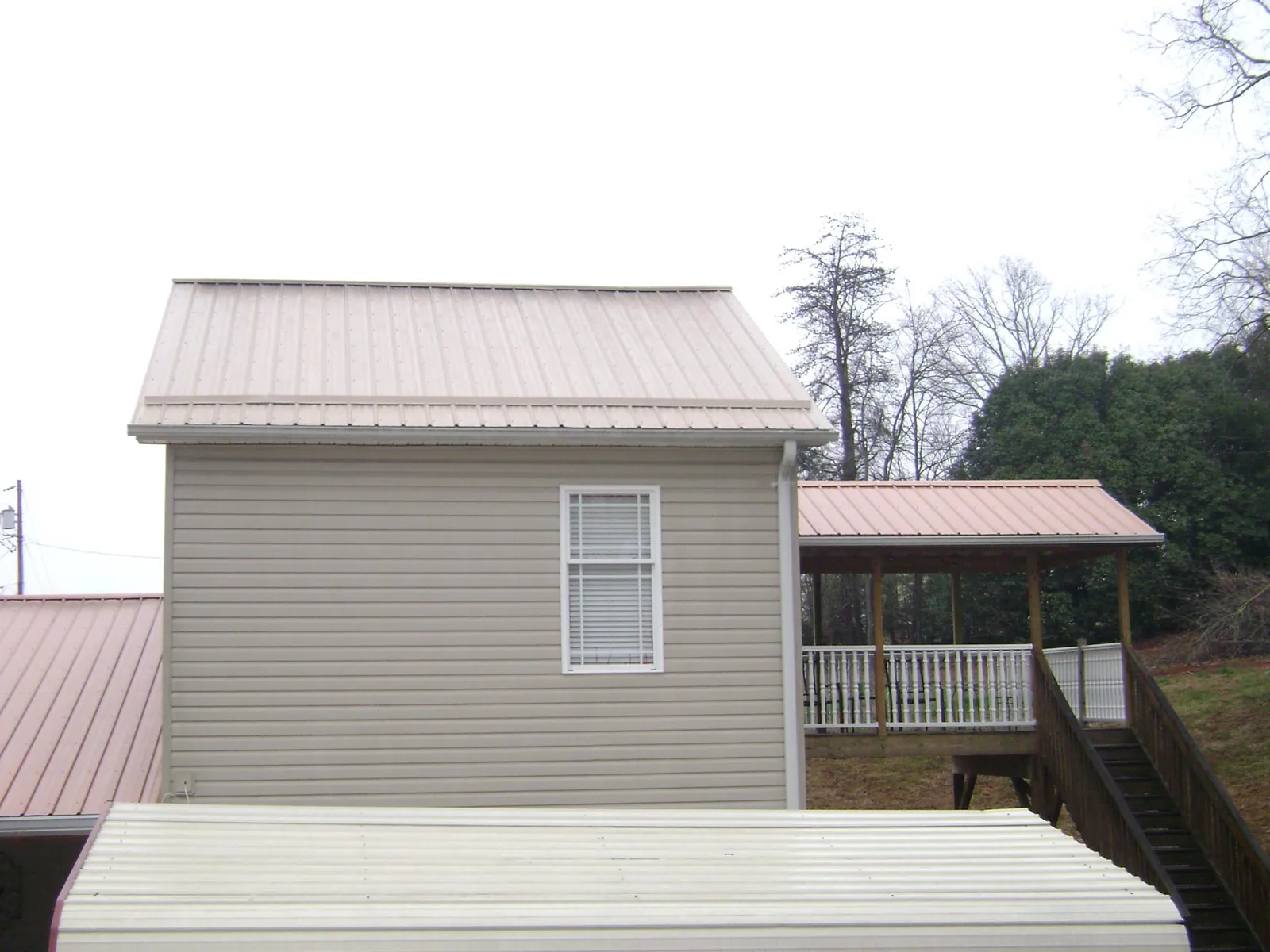 Tan metal roofs on a two story addition and attached porch, from a Roof Replacement job in Port Hueneme Cbc Base